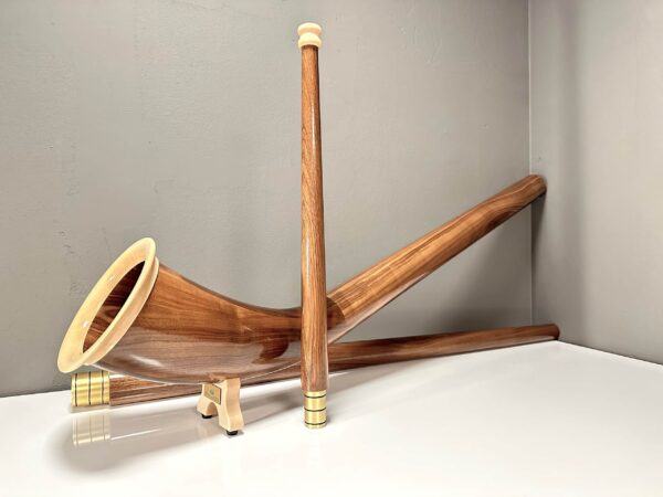 Elegantes Alphorn mit edlen Holzmundstücken in einem schlichten Raum, präsentiert von NATURINSTRUMENTE Heimatklang.