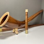 Edles Alphorn aus glattem, polierten Holz mit hochwertigem Mundstück, präsentiert auf einer weißen Oberfläche.