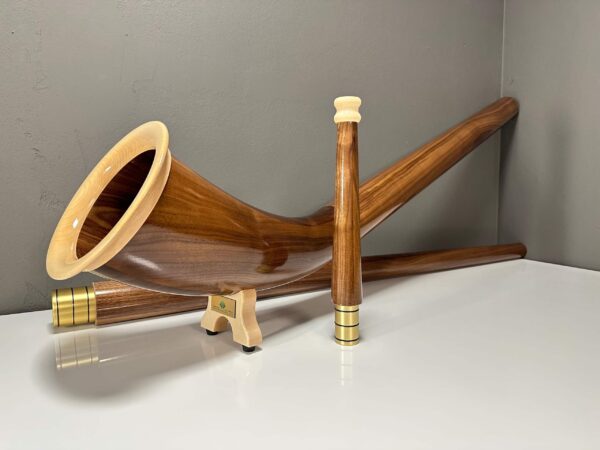 Edles Alphorn aus glattem, polierten Holz mit hochwertigem Mundstück, präsentiert auf einer weißen Oberfläche.