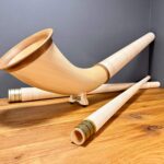 Hochwertiges Alphorn mit Holzmundstück auf Holztisch, perfekter Klang für Naturinstrumente-Enthusiasten bei Heimatklang.
