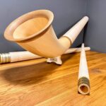 Hochwertiges Alphorn mit detailreichem Holzmundstück, ruhend auf Holztisch. Traditionelles Instrument für Heimatklang.
