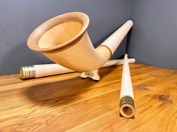 Hochwertiges Alphorn mit detailreichem Holzmundstück, ruhend auf Holztisch. Traditionelles Instrument für Heimatklang.