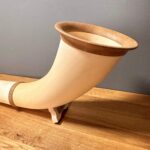 Holz-Alphorn auf Holzunterlage präsentiert, betont feine Handwerkskunst und hochwertige Materialien, ideal für Naturinstrumente-Enthusiasten.