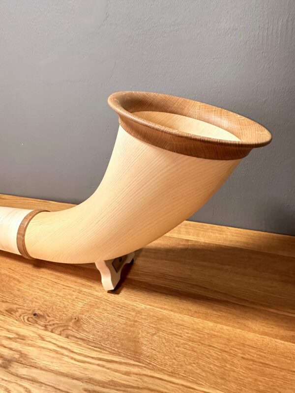 Holz-Alphorn auf Holzunterlage präsentiert, betont feine Handwerkskunst und hochwertige Materialien, ideal für Naturinstrumente-Enthusiasten.