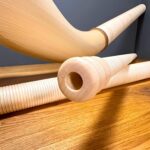 Hochwertige Alphörner mit feinen Holzmundstücken, auf Holztisch präsentiert, zeigen traditionelle Handwerkskunst bei Heimatklang.