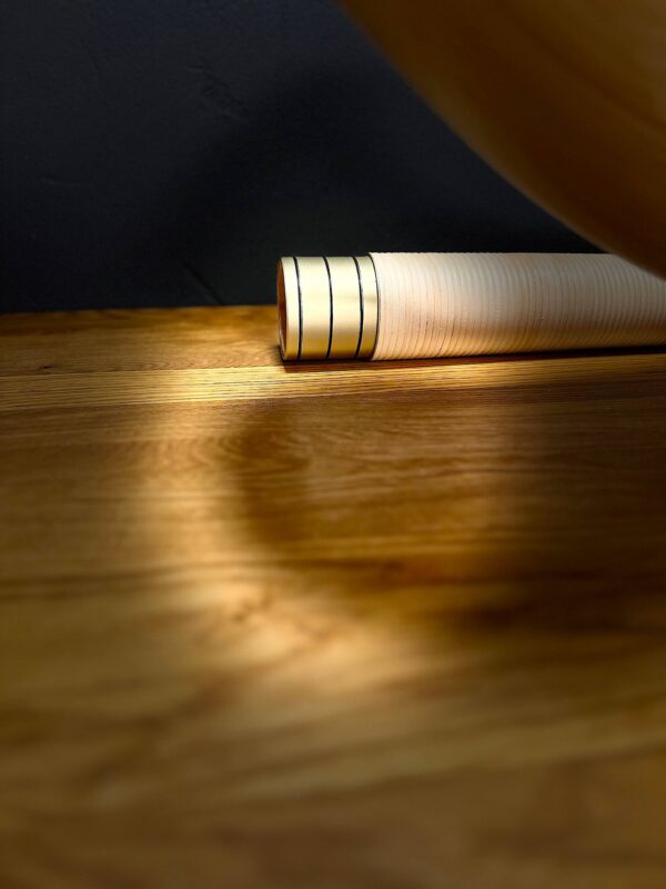 Elegantes Alphorn-Mundstück aus Holz auf einem Holztisch, warm beleuchtet für NATURINSTRUMENTE Heimatklang.