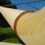 Detailaufnahme eines Alphorns aus hellem Holz mit einem dekorativen Holzring bei sonnigem Wetter. Perfekt für NATURINSTRUMENTE.