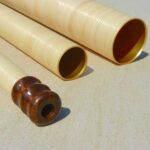 Hochwertige Alphorn-Rohre und Holzmundstück auf Steinboden, präsentiert von NATURINSTRUMENTE Heimatklang.