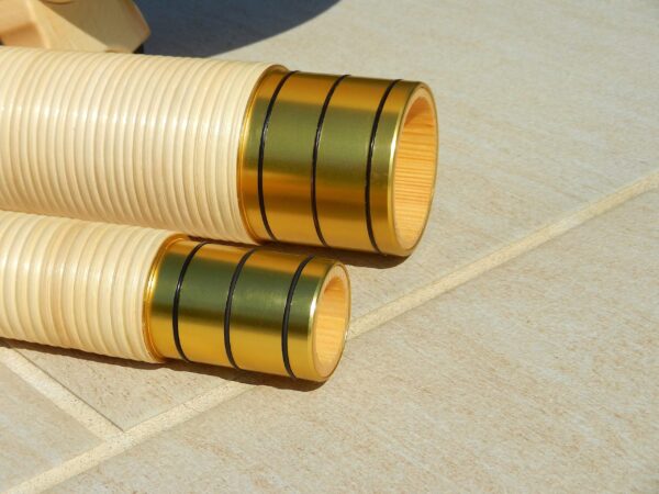 Detailaufnahme von zwei goldenen Mundstücken für Alphörner, die im Sonnenlicht glänzen und Qualität widerspiegeln.