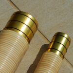 Zwei hochwertige Holzmundstücke für Alphörner, verziert mit goldenen Ringen, liegen auf einer Holzoberfläche.