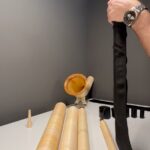 Montage eines Alphorns mit Holzteilen auf weißem Tisch, umgeben von Mundstücken und schwarzem Abdeckstoff.