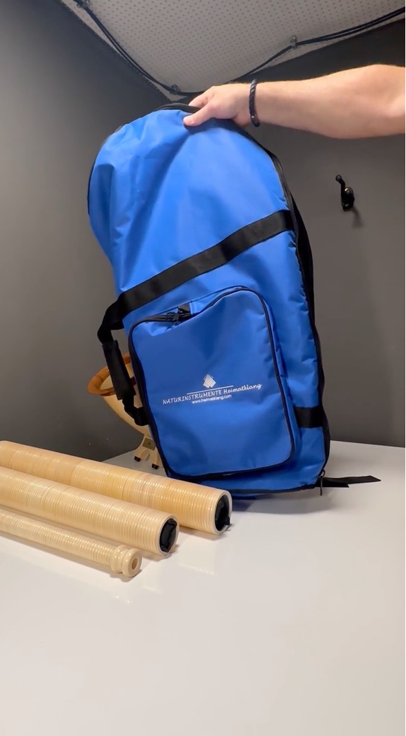 Blauer Tragerucksack für Alphörner und drei Holzrohr-Mundstücke auf Tisch von NATURINSTRUMENTE Heimatklang.