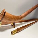 Hochwertiges Alphorn aus Holz mit präzise gearbeiteten Mundstücken, präsentiert auf einem weißen Untergrund.