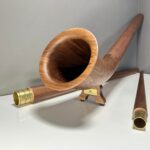 Edles Alphorn aus Holz mit goldenen Mundstücken, präsentiert auf weißem Untergrund, Naturinstrumente Heimatklang.