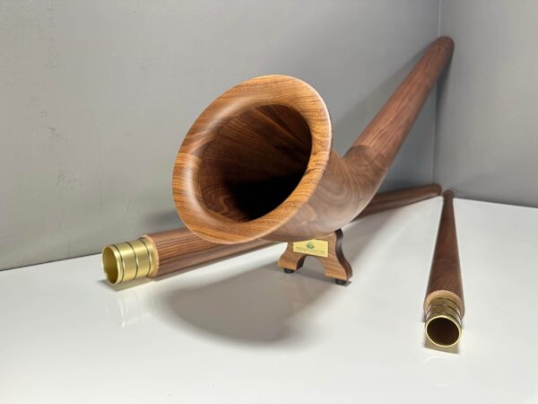 Edles Alphorn aus Holz mit goldenen Mundstücken, präsentiert auf weißem Untergrund, Naturinstrumente Heimatklang.