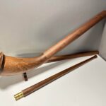 Edles Alphorn mit zwei Holzmundstücken auf weißem Hintergrund, präsentiert auf der NATURINSTRUMENTE Heimatklang-Website.
