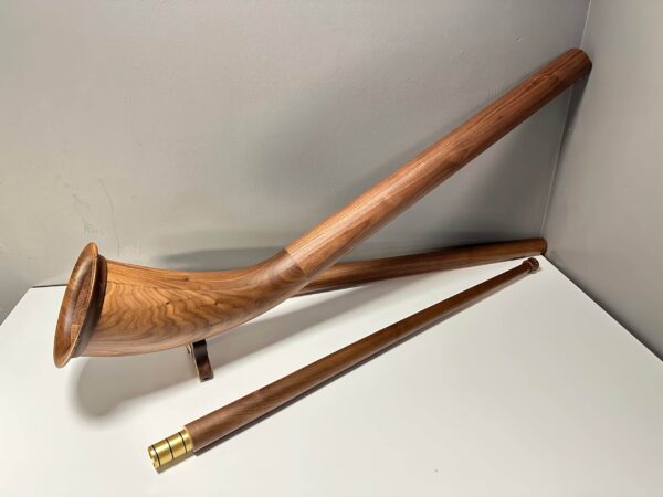 Edles Alphorn mit zwei Holzmundstücken auf weißem Hintergrund, präsentiert auf der NATURINSTRUMENTE Heimatklang-Website.