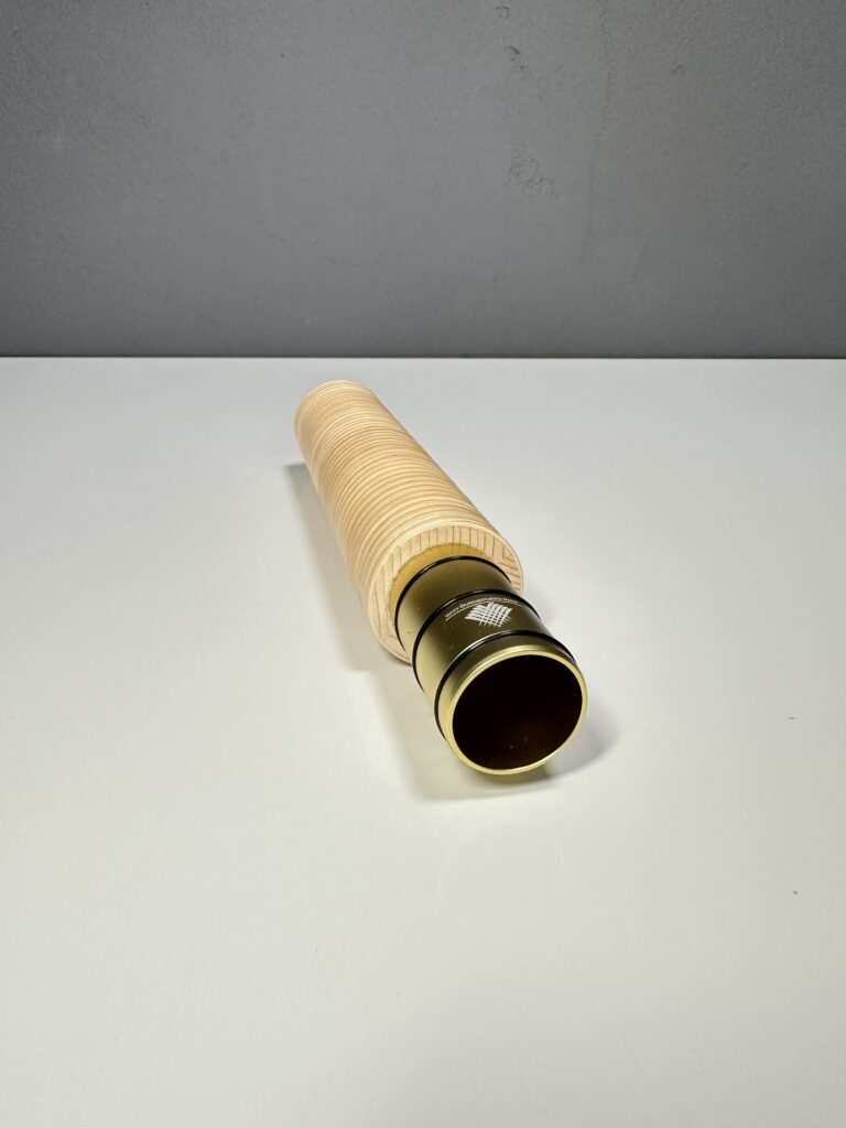 Close-up of a high-quality wooden mouthpiece for an alphorn, presented on a gray surface.