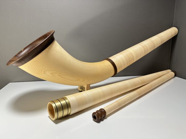 Hochwertiges Alphorn mit separatem Holzmundstück, präsentiert auf einem Tisch, ideal für Naturinstrumente-Enthusiasten.