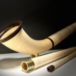 Hochwertiges Alphorn aus Holz mit separaten Röhren und präzise gearbeiteten Mundstücken auf dunklem Hintergrund.