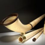 Alphorn aus hellem Holz mit Mundstück und Zubehör auf weißem Untergrund, gefertigt für Heimatklang Naturinstrumente.