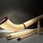 Alphorn mit Holzmundstück und Zubehör auf weißem Tisch, ideal für traditionelle Alpenmusik.