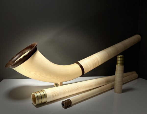 Alphorn mit Holzmundstück und Zubehör auf weißem Tisch, ideal für traditionelle Alpenmusik.