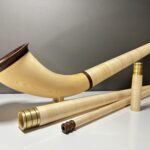 Alphorn aus hellem Holz mit mehreren abnehmbaren Sektionen und einem hochwertigen Mundstück auf weißem Hintergrund.