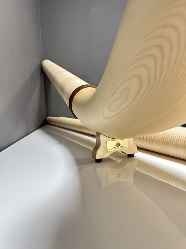 Alphorn made of light wood stands on a shiny base, mirror finish visible, high-quality workmanship for NATURINSTRUMENTE Heimatklang.