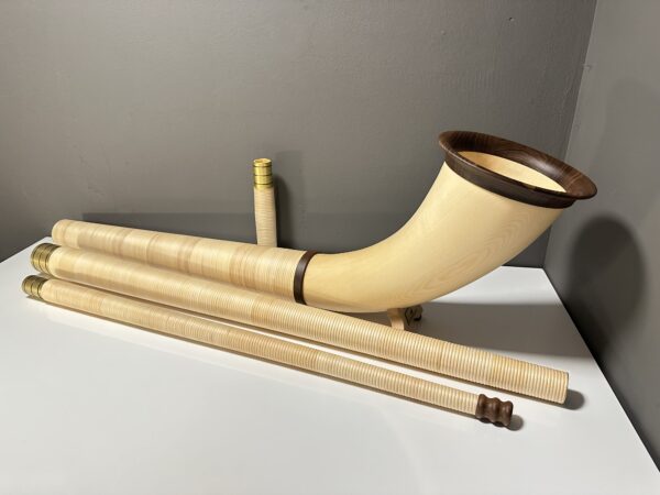 Alphorn mit Holzmundstücken auf weißem Tisch, ideal für Alpklänge und als hochwertiges Alphorn Zubehör.
