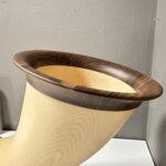 Alphorn aus hochwertigem Holz mit elegantem Mundstück, präsentiert vor neutraler Wand.