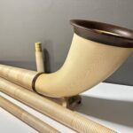 Alphorn mit Holzmundstück und Segmenten auf weißer Oberfläche, präsentiert von NATURINSTRUMENTE Heimatklang.