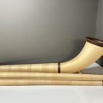Hochwertiges Alphorn mit feinem Holzmundstück auf weißem Hintergrund, perfekt für Naturklang-Enthusiasten.