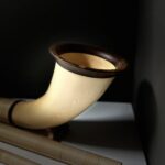 Alphorn mit elegantem Holzmundstück in Nahaufnahme, präsentiert in stilvoller, minimalistischer Umgebung.