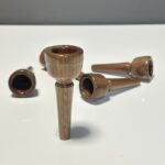 Handgefertigte Holzmundstücke für Alphörner, elegant auf weißem Hintergrund arrangiert, für nativen Klanggenuss.