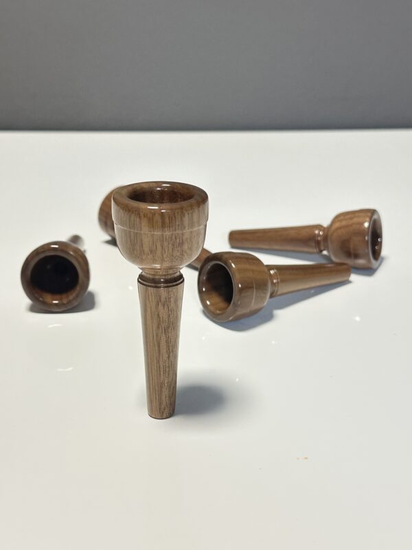 Handgefertigte Holzmundstücke für Alphörner, elegant auf weißem Hintergrund arrangiert, für nativen Klanggenuss.